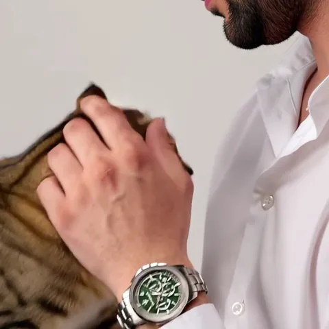 The hand drops to a bengal cat. The watch moves into shadow, and the green dial reads almost black — the colour holds on
