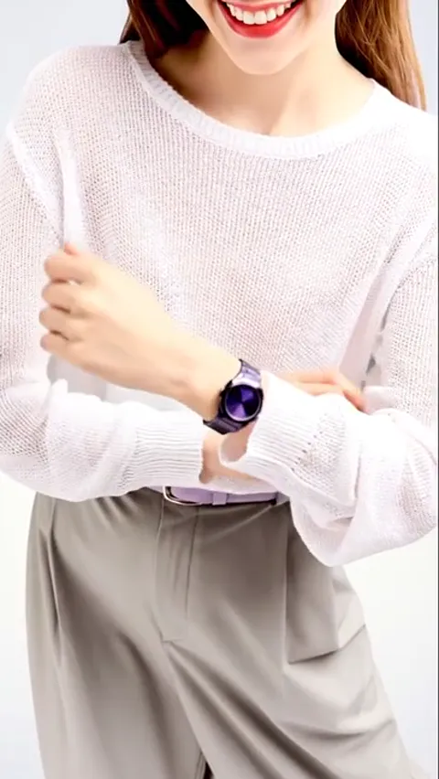 A woman in a fine white sweater adjusts her sleeve: a watch on her wrist with a dark bracelet and an iridescent purple d