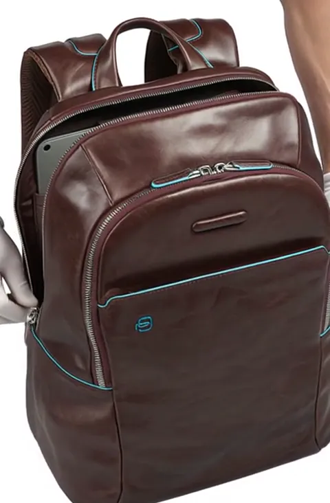 A compartment opens to reveal a laptop. The tech pocket is separate, padded, and opens independently of the main volume.
