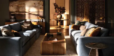A living room in a wide shot: two large sofas facing each other, a low wooden table between them, a rug, a picture above