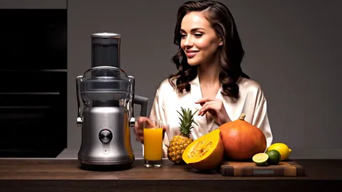 The finale: the woman with her glass, the machine entire in frame. Eight seconds have shown the appliance at work rather