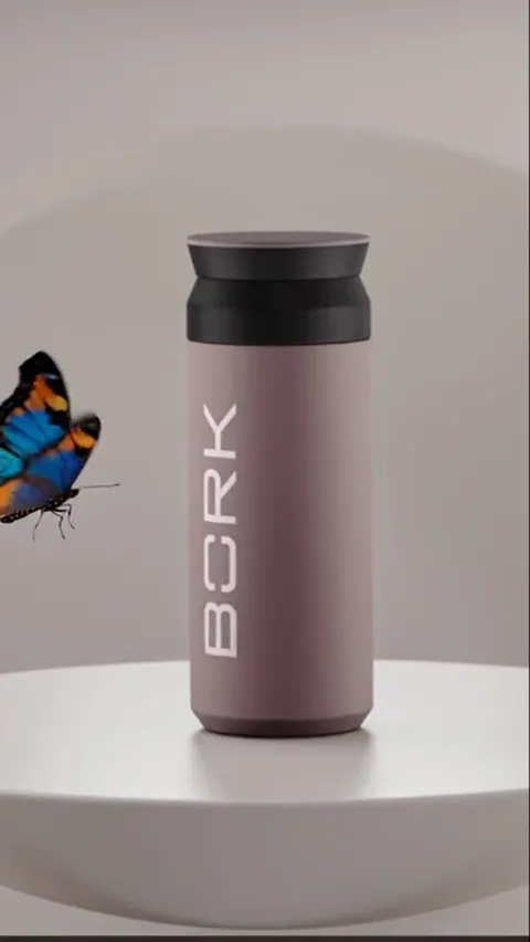 A travel mug stands on a white plinth in a dark studio: a dusty pink matte body, a black lid, a logo at the side. A butt