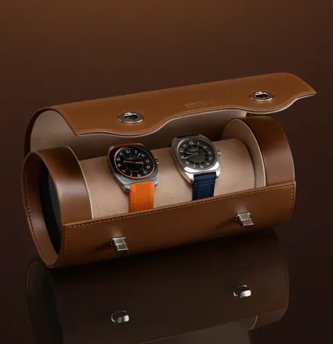 The case is open: a beige suede cushion inside with two watches on it. It holds exactly two, and there is a divider betw