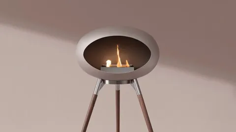 The bio fireplace close: a round bowl of burning flame on three slim legs. A pale ground, nothing in frame but the fire.