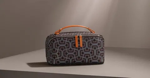 The case stands on a plinth in an empty, bright studio: a grey body with a graphic pattern of loops and lines, an orange
