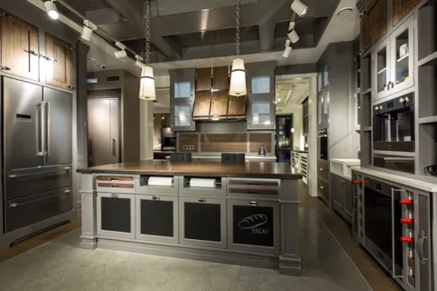The camera moves forward along the island. The island is double-sided: a working zone on one face, oven housings on the 