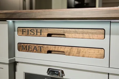 Close on a kitchen drawer front: two wooden ends protrude from the carcass, burned with the words FISH and MEAT. So far 