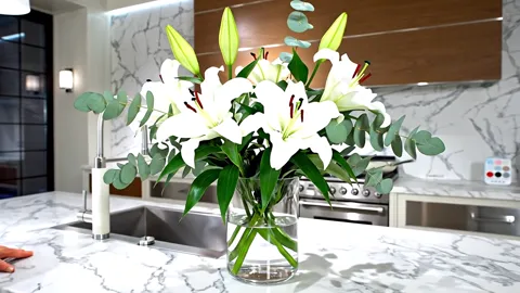The finale: the bouquet on the island, the kitchen behind it. Eight seconds have shown the kitchen as a lived-in space r