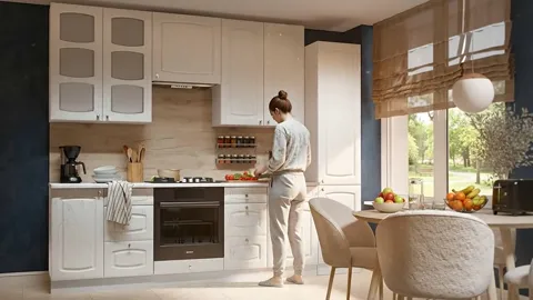 A kitchen in white fronts by a window: upper cabinets with glazed inserts, a built-in oven, a dining area to the right. 