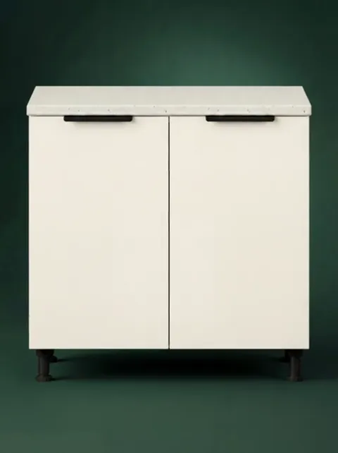 A wide module against dark green: two hinged doors with black handles, a stone worktop. So far, an ordinary kitchen cabi