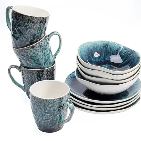 A tableware set on white: mugs, bowls and plates in a speckled turquoise glaze. The stacks stand together, the white gro