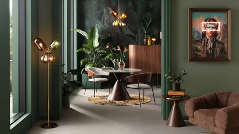 A dining corner in dark green walls: a round marble table on a conical base, two chairs, a sideboard, a floor lamp and a