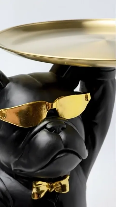 A close view of the figure: a black bulldog in a suit with gold sunglasses and a bow tie holds a gold tray above its hea
