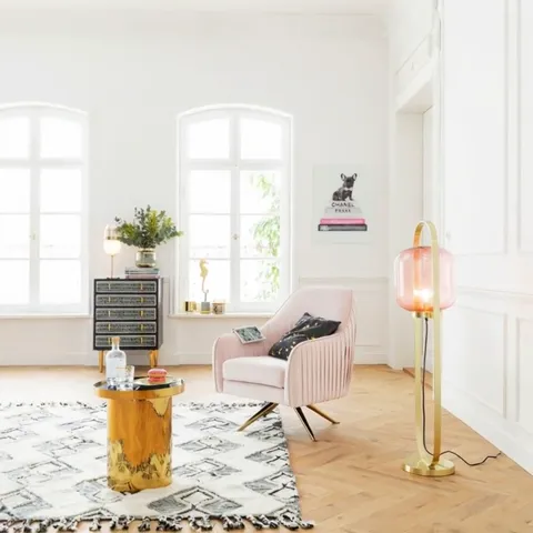 The camera pulls back and the room opens up: a chest, a rug, a floor lamp, a side table. The picture becomes one object 