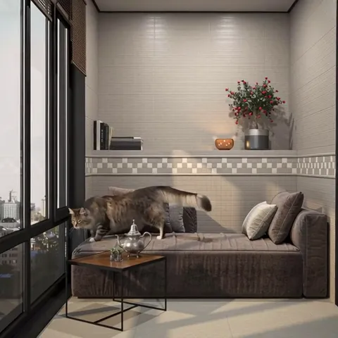 The cat walks along the daybed beside the wall. Its size gives the scale of the mosaic border: a single square is about 