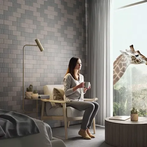 She sits down; the giraffe looks in almost at the glass. Its head beside the window opening gives the scale of the whole