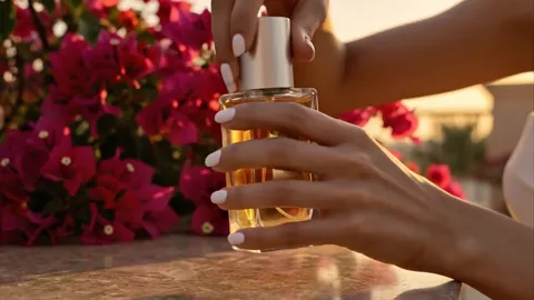 A woman's hand takes the bottle. The glass is thick: light passes through and casts an amber shadow on the marble.