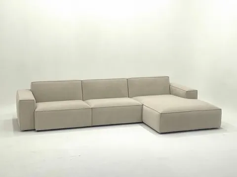 The sofa nearly in profile against white: three seat modules and a wide ottoman, a low back, substantial arms. The first
