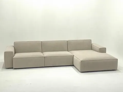 The camera swings on an arc — the ottoman comes forward. It becomes clear this is a separate module pushed up against th