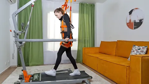 A step is taken and the harness takes part of the weight. The system is legible: the straps run from the waist and thigh