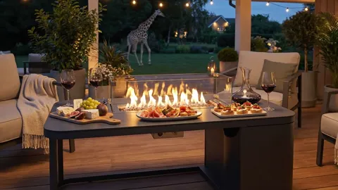 Closer to the fire: a giraffe stands in the dusk behind it. The absurdity arrives quietly, without stealing attention fr