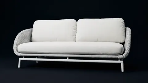 The ground goes near-black, the sofa in profile. The frame lifts the shell off the floor — a hand's width of clearance b