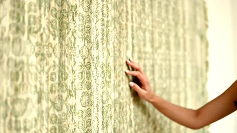 The finale: her hand still on the rug, the pattern filling nearly the whole frame. Eight seconds have shown both the des