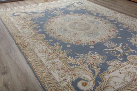 The rug in a room with full-height windows: a blue-grey field with a cream Savonnerie ornament — a central medallion, fo