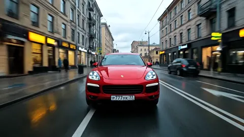A city street, wet asphalt: a red crossover drives away from the camera, reflecting the shopfronts. The buildings blur p