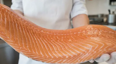 Macro on the cut: white lines of fat between the muscle flakes and an even orange tone with no grey patches.