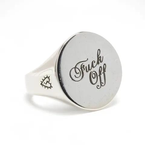 The signet ring close on white: a wide round face carrying a calligraphic engraving, a small symbol on the shoulder of t