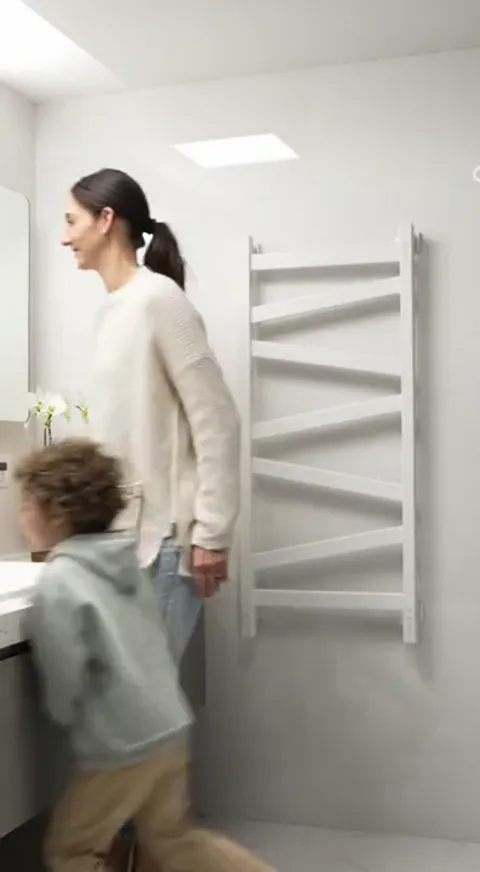 A third bathroom with a rooflight: a child runs past the radiator, a woman at the basin. The unit in a domestic scene ra