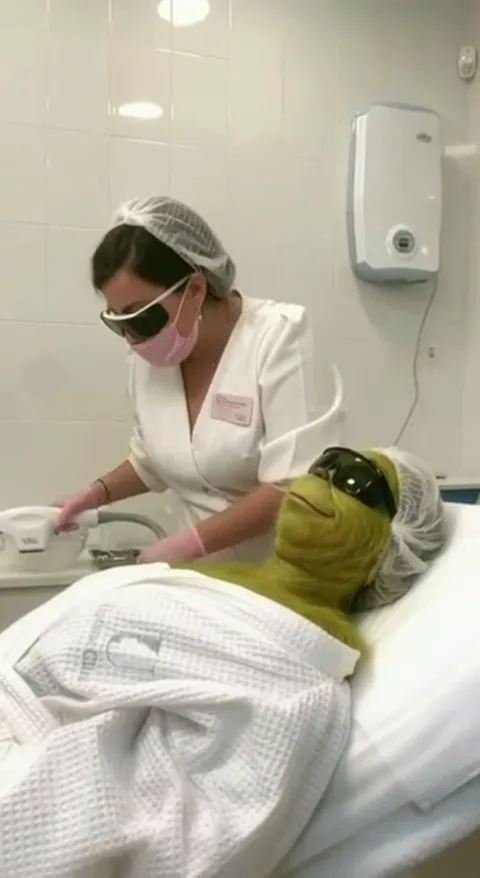 A cut: the therapist in a gown, cap and protective goggles switches on a device. A real room with real equipment in fram