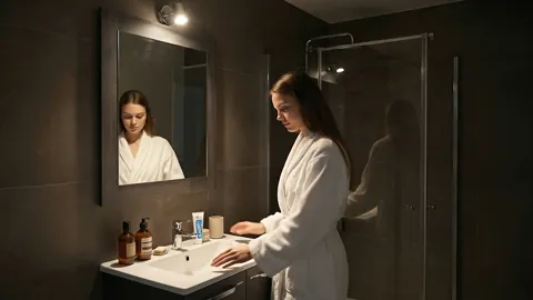 She leans on the counter. The width of the counter against the basin is visible: there is working space at the sides, no