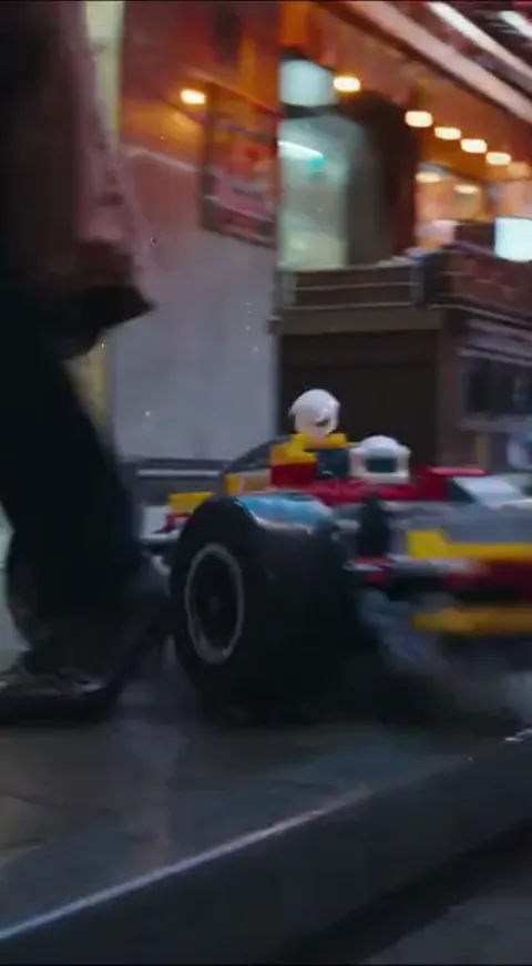 The car passes a pedestrian's feet. The scale is set: it is about the size of a shoe, filmed as though it were a full-si