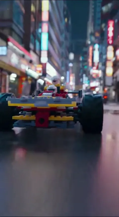 The finale: the car centre-frame, neon behind. Ten seconds have made a construction-set part the hero of a commercial wi