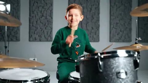 He leans toward the snare and the fabric pulls across the shoulder. The fit reads: the sweatshirt is loose but not baggy