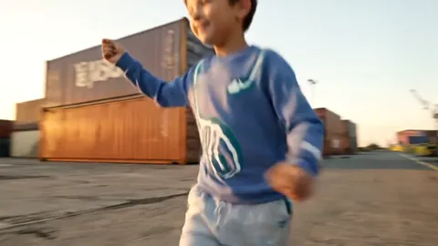 Framed to the chest, the boy in motion. The chest print is visible, and the sweatshirt is loose: the fabric folds at the