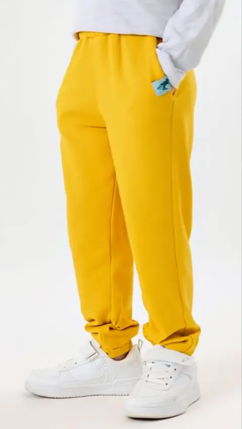 White ground, framed from the waist: bright yellow children's trousers in dense loopback, a broad elastic waistband, a l