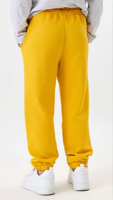 From behind: no back pockets, an even centre seam. The length against the sneakers reads — the trousers just cover the a