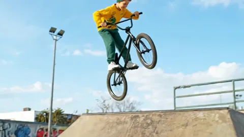 A jump: the bike in the air, the boy at the top of the arc. The hoodie does not ride up and the trousers do not catch in